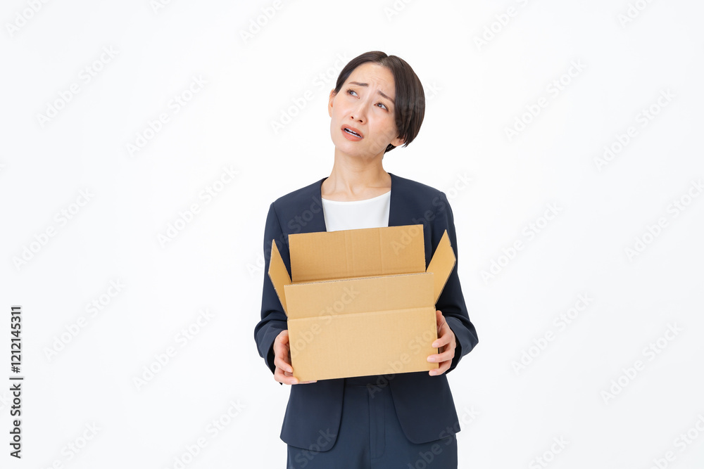 ダンボールを持ち困るスーツを着た女性 ダンボールを持ち困るスーツを着た女性