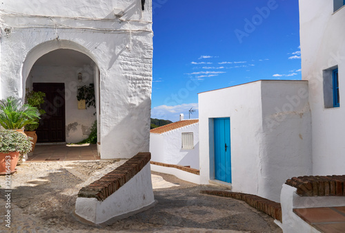 Street in the village of Frigiliana, with white walls and blue doors and windows on a sunny morning. Malaga, Spain.