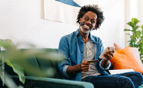 Happy mature man smiling and enjoying online shopping on his smartphone at home