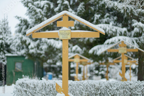 Cross is covered in snow and has a sign on it that says 