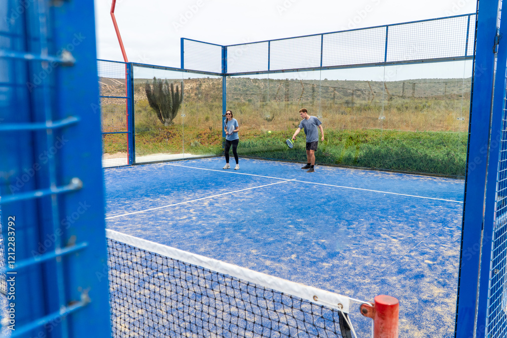 An outdoor padel court with players in action, under a cloudy sky, creating a dynamic and intense atmosphere for the match.