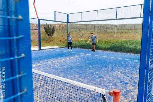 Obraz na płótnie An outdoor padel court with players in action, under a cloudy sky, creating a dynamic and intense atmosphere for the match. w salonie