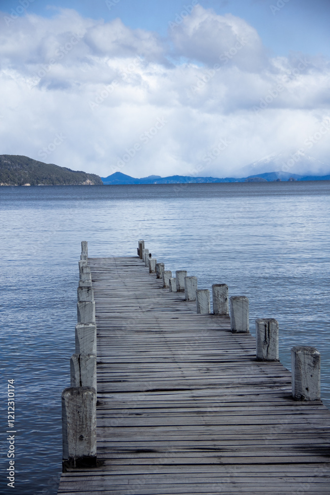 Fototapeta premium Dock in lake, Patagonia lake, mountains in the background, calm water horizon, blue sunset