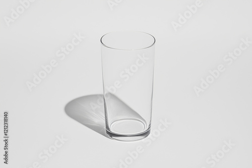 Empty Glass with Shadow: A tall, cylindrical drinking glass sits on a surface, casting a subtle shadow. Minimalist and clean aesthetic. Perfect for product displays, mockups, or backgrounds. 