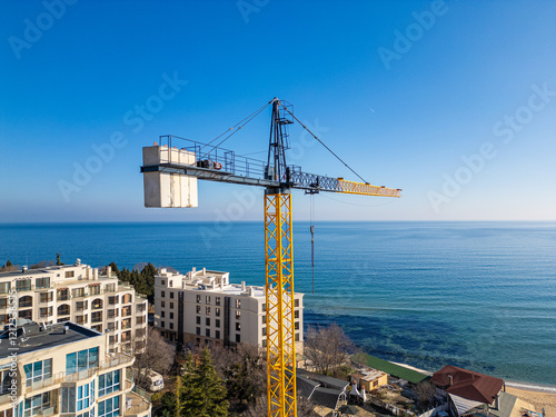 New hotel or residential complex under construction on the picturesque Kabakum Beach near Varna, Bulgaria. Tower cranes, metal structures, and the seaside view define this vibrant sunny worksite photo