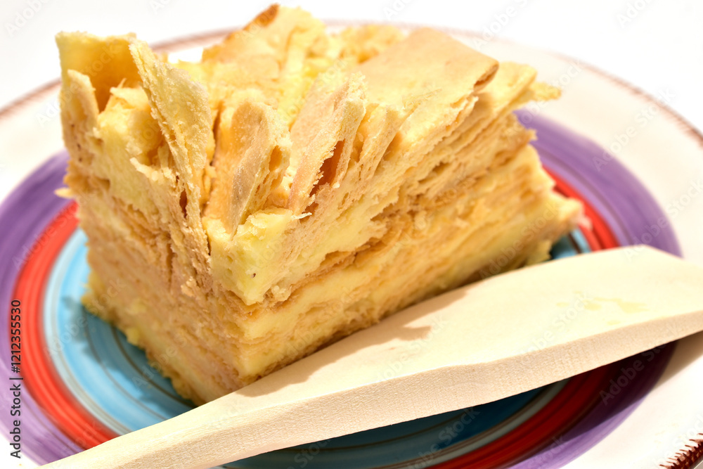 Layered cake with cream called Napoleon lies on a ceramic plate, close-up Layered cake with cream called Napoleon lies on a ceramic plate, close-up