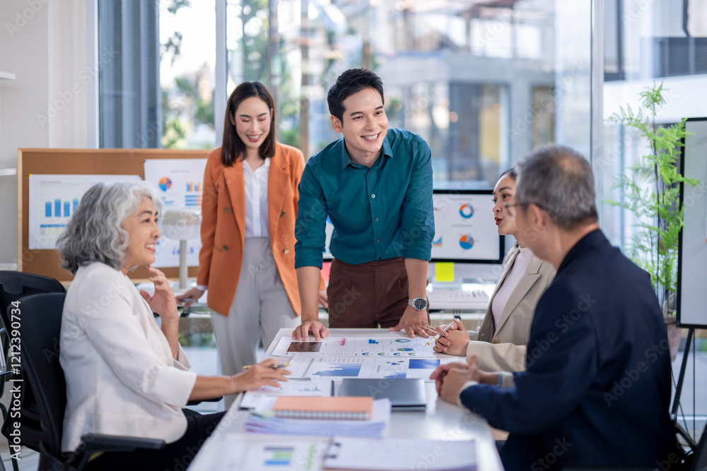 A group of people are gathered around a table with a lot of papers and graphs A group of people are gathered around a table with a lot of papers and graphs