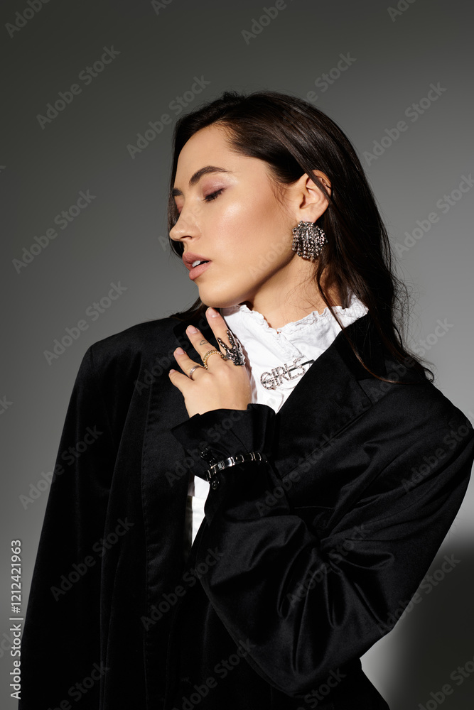 Young woman with shiny brown hair poses gracefully in a sophisticated outfit against grey backdrop. Young woman with shiny brown hair poses gracefully in a sophisticated outfit against grey backdrop.