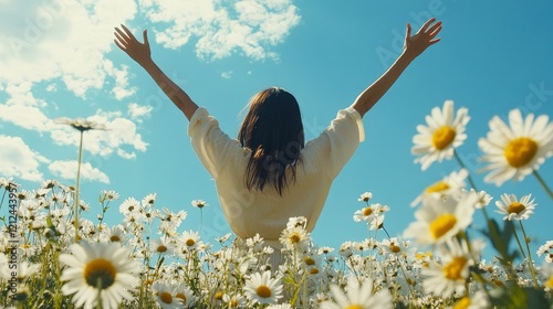 Woman in a field of daisies with arms raised enjoying summer