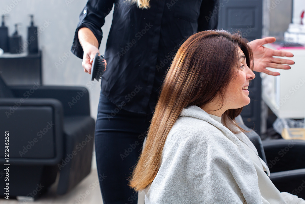 Hairstylist combs hair with hairbrush for a young female client Hairstylist combs hair with hairbrush for a young female client