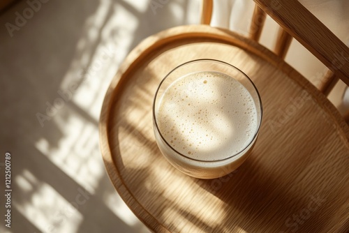 Warm sunlight dances on wooden chair, illuminating glass of frot photo