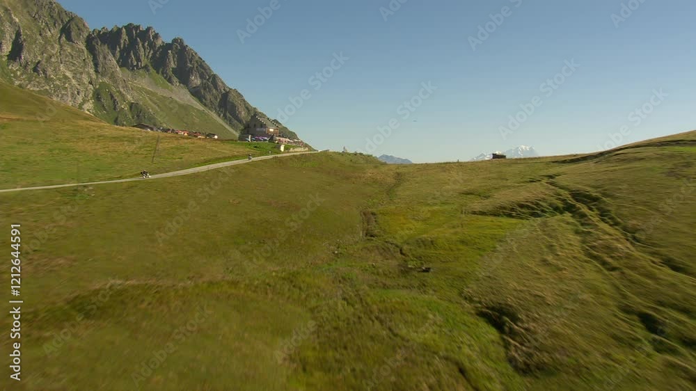 Survol panorama d'une route de montagne avec traversée d'un col et découverte des sommets et prairie