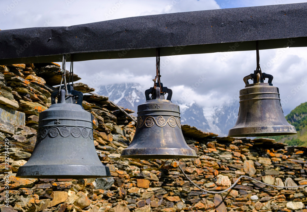 Obraz premium Traditional bronze bells hanging in front of a stone wall