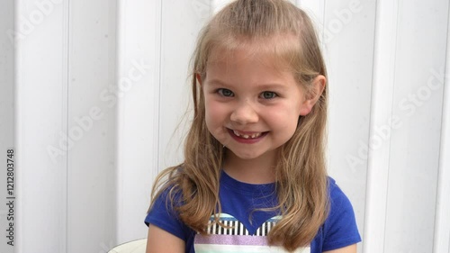 Cute Caucasian preschool girl wiggling her baby tooth with her finger which is ready to fall off. Dentistry concept. Happy healthy child about to lose a tooth