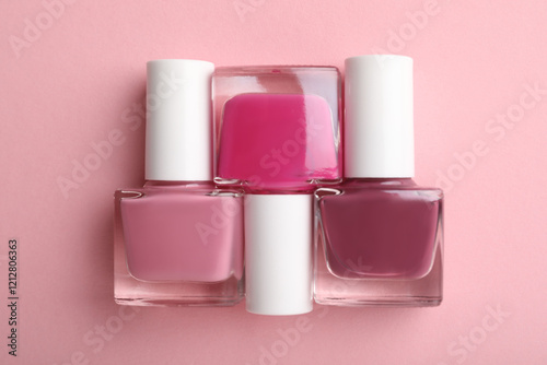 Set of different nail polishes in bottles on pink background, flat lay photo