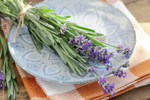 Lavender herbal bouquet in a vintahe plate and textile with flowers on wooden rustic background, closeup, sleep and skin healing plant, natural medicine and naturopathy concept photo