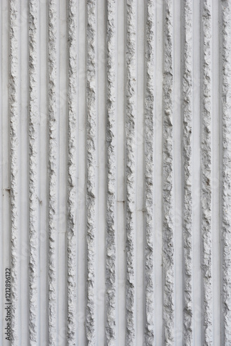 The texture of a concrete facade with a vertical, ribbed pattern