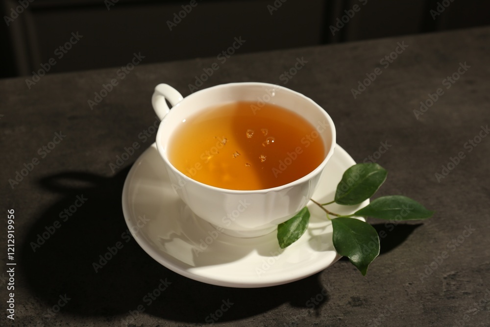 Refreshing green tea in cup and leaves on dark textured table, closeup Refreshing green tea in cup and leaves on dark textured table, closeup