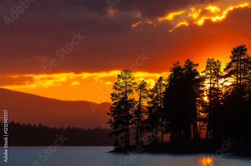 Beautiful sunset view behind trees at Burusjön lake in Sweden creates a serene atmosphere photo