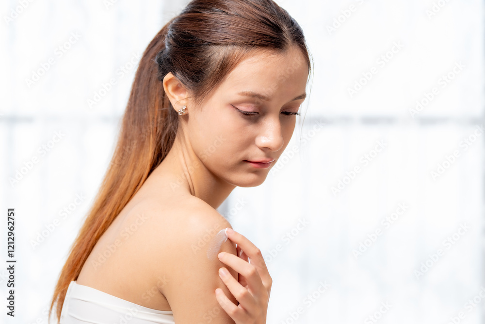 young woman applying cream to her shoulder, showcasing skincare routine and self care. soft lighting enhances serene atmosphere young woman applying cream to her shoulder, showcasing skincare routine and self care. soft lighting enhances serene atmosphere