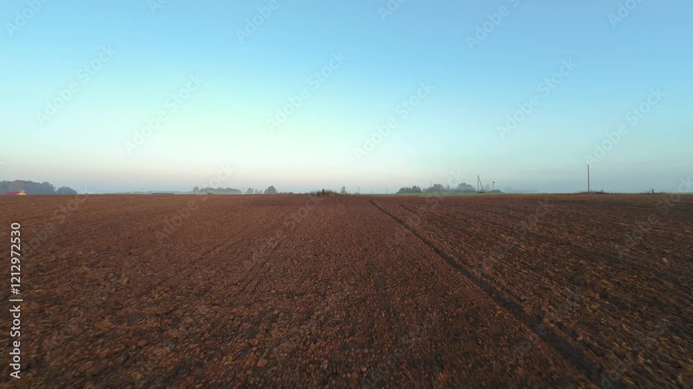 Drone view of freshly plowed field under clear morning sky soft light of sunrise highlights texture of soil, creating serene and productive rural scene plowed field at sunrise with clear sky Drone view of freshly plowed field under clear morning sky soft light of sunrise highlights texture of soil, creating serene and productive rural scene plowed field at sunrise with clear sky