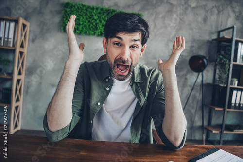 Frustrated young man expressing anger at workplace in casual office environment photo