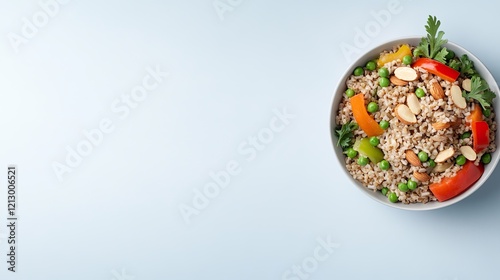 clean top-down view of brown rice salad with green peas bell peppers and almonds placed on smooth white backdrop with photo