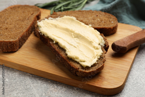 Fotografía Fresh bread with butter and knife on grey table, closeup