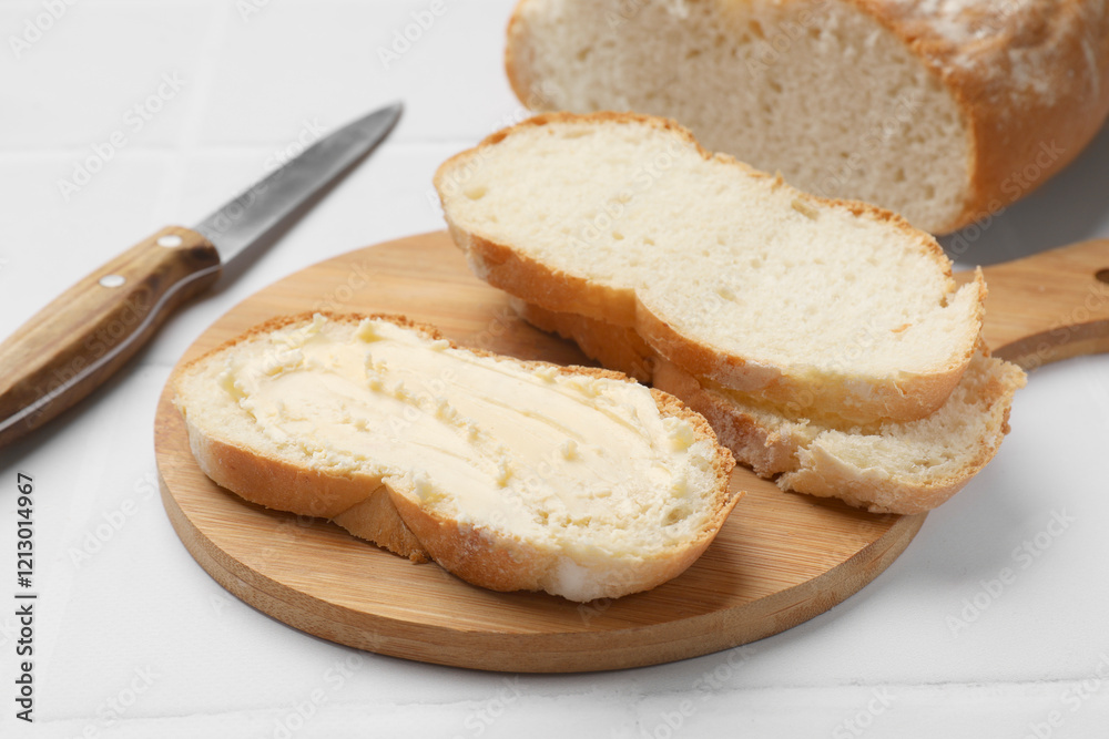 Fresh bread with butter and knife on white tiled table, closeup Fresh bread with butter and knife on white tiled table, closeup