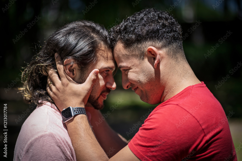 Couple of latin men hugging each other putting their heads together in a park Couple of latin men hugging each other putting their heads together in a park