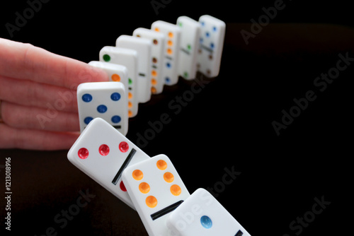 person stopping dominoes with hand finger from falling probability chance future cause and effect causality protection security metaphor planning games backdrop photo