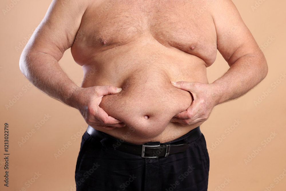 Naklejka premium Man with excessive belly fat on beige background, closeup. Overweight problem