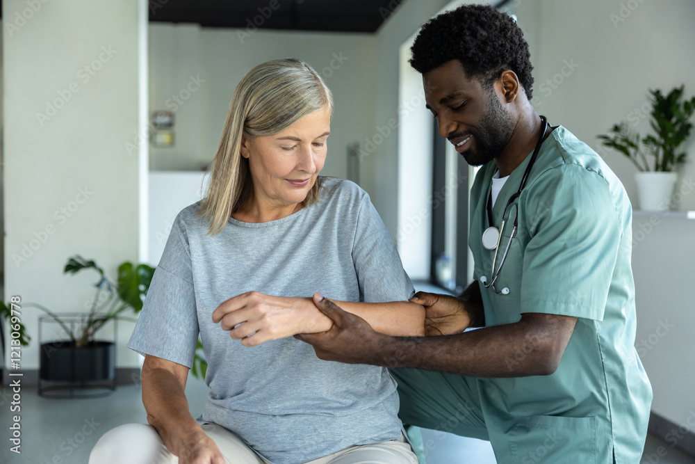 Obraz premium African American male doctor hand doing physical therapy by extending elbow of mature female patient