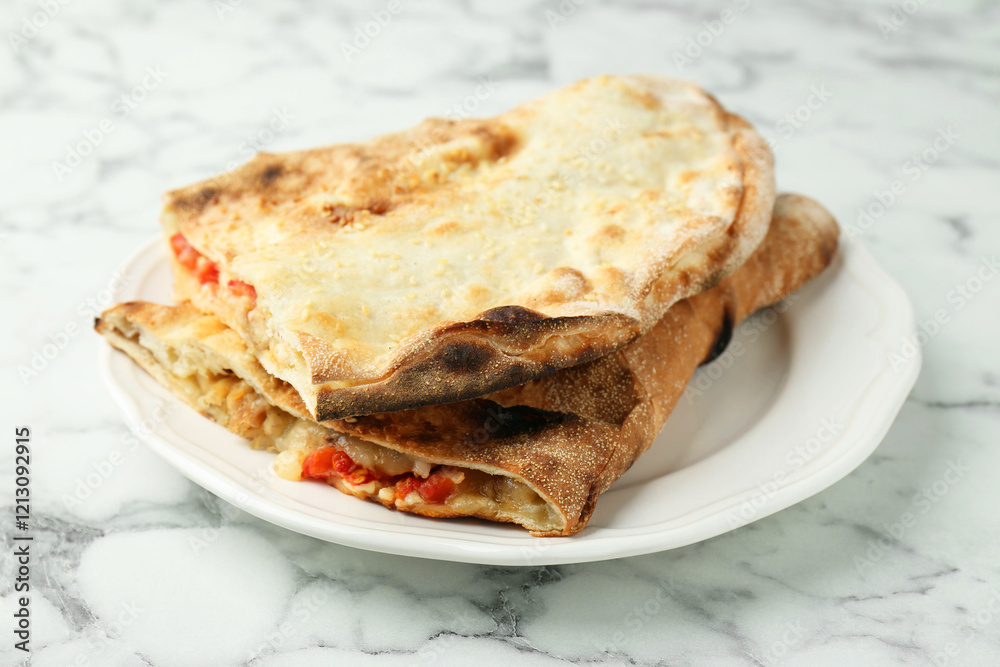 Halves of tasty calzone with meat, cheese and tomato on white marble table, closeup Halves of tasty calzone with meat, cheese and tomato on white marble table, closeup