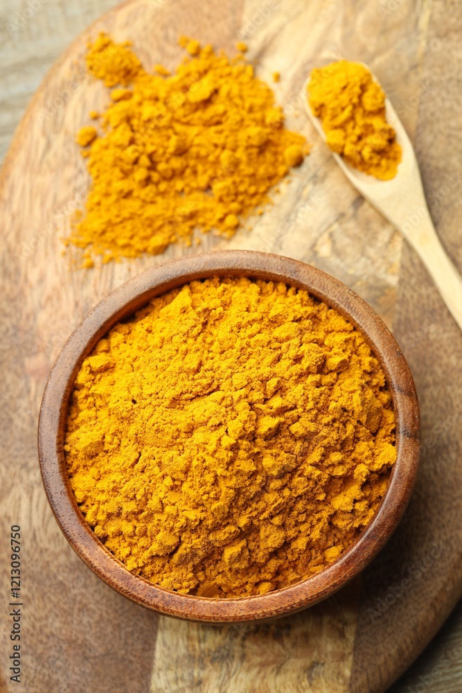 Turmeric powder in bowl and spoon on table, top view Turmeric powder in bowl and spoon on table, top view