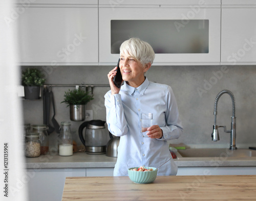 businesswoman busy home woman mature kitchen morning hydration mobile call smartphone phone healthy glass water drink business getting ready photo