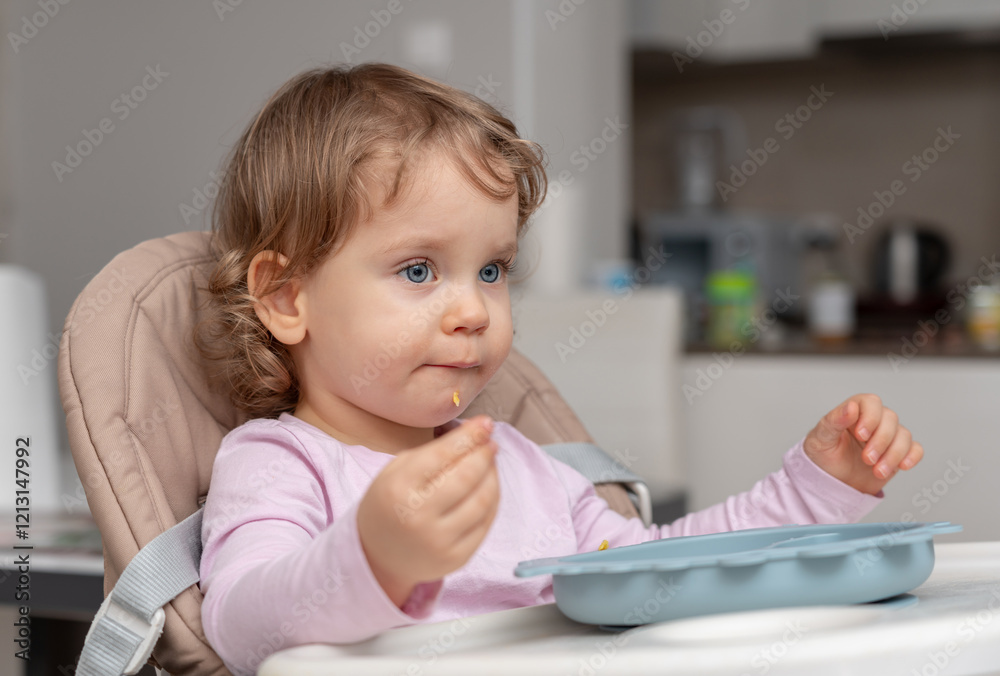 A curious toddler concentrating on self-feeding during a calm mealtime. A curious toddler concentrating on self-feeding during a calm mealtime.