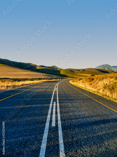 Obraz na płótnie Vertical view of the scenic R43 road winding through golden harvested fields at sunset, Caledon, South Africa w salonie