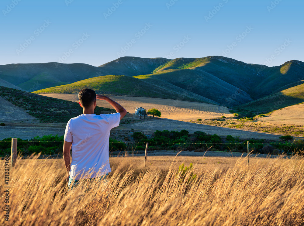 A young tourist enjoying the view of Overberg rolling hills during sunset, Caledon, South Africa