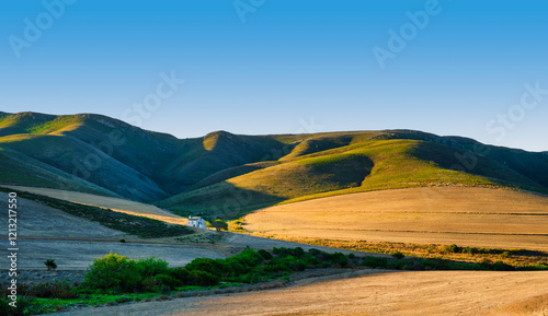 Obraz na płótnie Panorama shot of a farmhouse in the rolling hills of Overberg during sunset, Caledon, South Africa w salonie