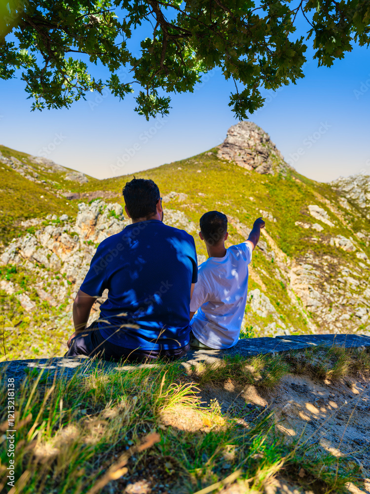 Vertical shot of two friends enjoying the view of Franschhoek Mountain while sitting under a tree, Franschhoek, South Africa