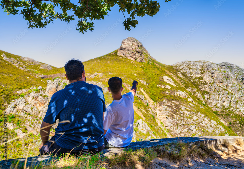 Two friends enjoying the view of Franschhoek Mountain while sitting under a tree, Franschhoek, South Africa