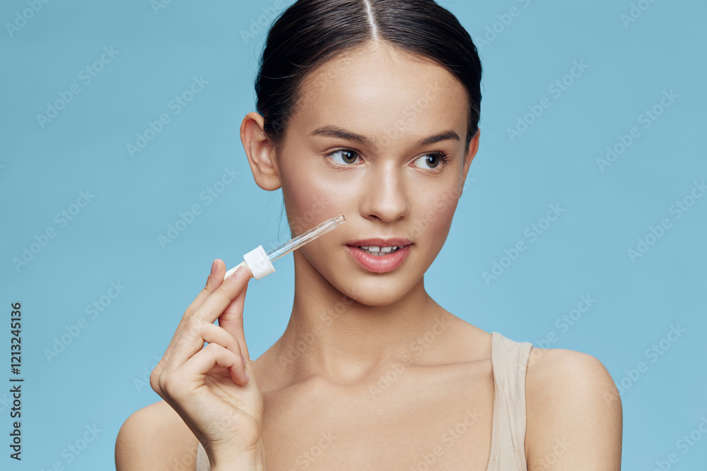 Young woman applying serum on her face with a dropper, showcasing healthy skin and natural beauty against a soft blue background Young woman applying serum on her face with a dropper, showcasing healthy skin and natural beauty against a soft blue background