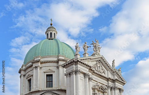 The top front gable of the New Cathedral or Duomo Nuovo with blue sky and white fluffy clouds in Brescia, Italy