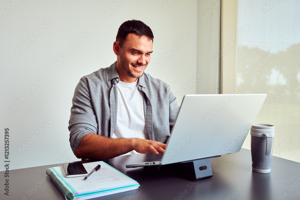Young businessman smiling and using laptop computer while working from office Young businessman smiling and using laptop computer while working from office