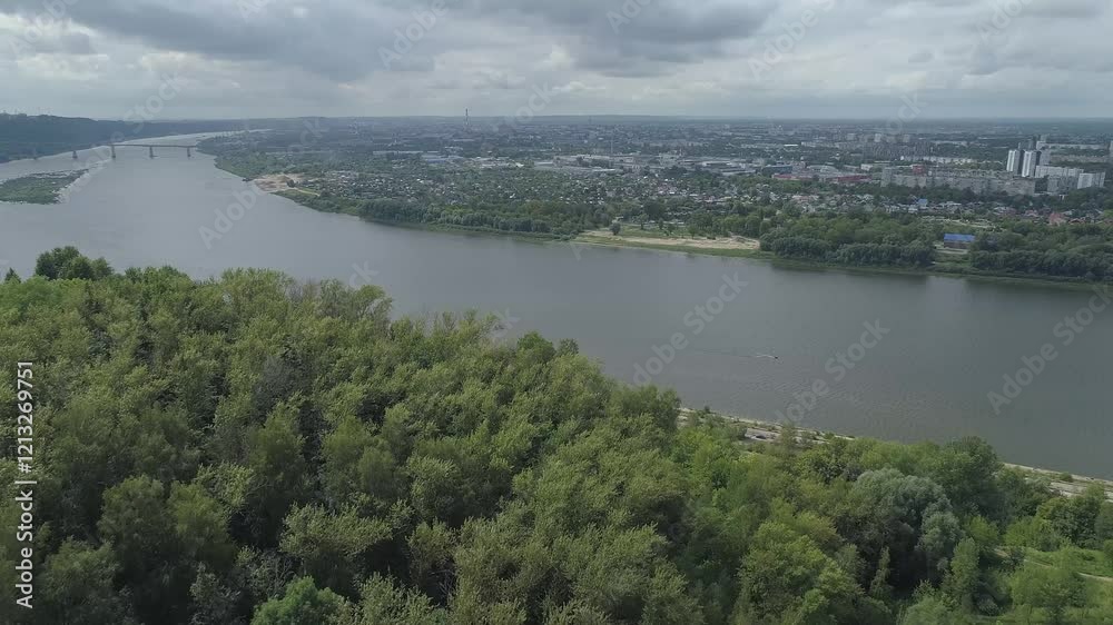 City with a river running through it. The river is surrounded by trees and the city is full of buildings. The city of Nizhny Novgorod, near the Oka River. Russia City with a river running through it. The river is surrounded by trees and the city is full of buildings. The city of Nizhny Novgorod, near the Oka River. Russia