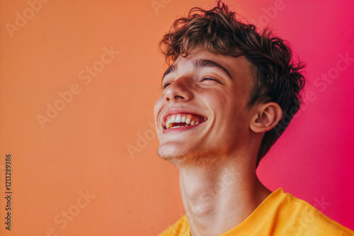 The image shows a person with curly hair, wearing a yellow shirt, smiling against a vibrant orange and pink background