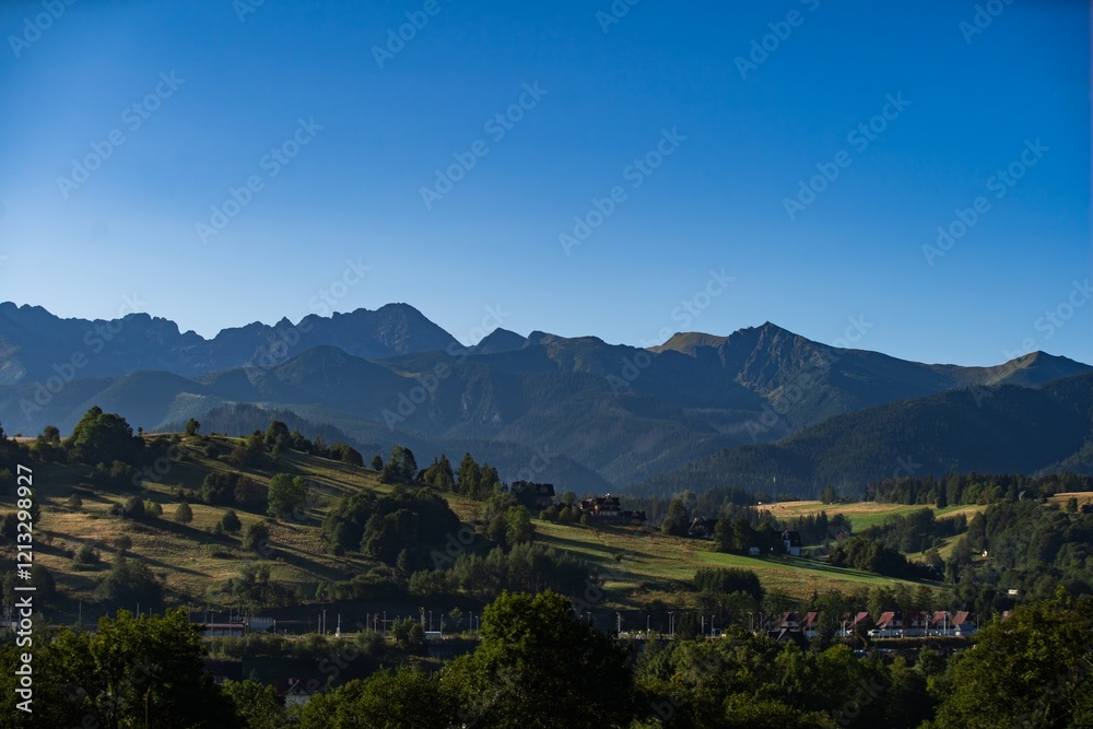Naklejka premium Breathtaking view of mountain range under clear blue sky during early morning light in a serene landscape setting