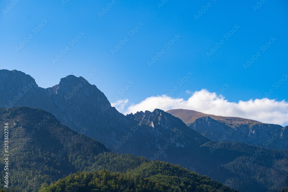 Mountains under a clear blue sky with slight cloud coverage in a serene natural landscape Mountains under a clear blue sky with slight cloud coverage in a serene natural landscape