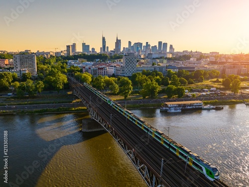 Vibrant sunset over the Vistula River with train crossing the bridge in Warsaw's skyline